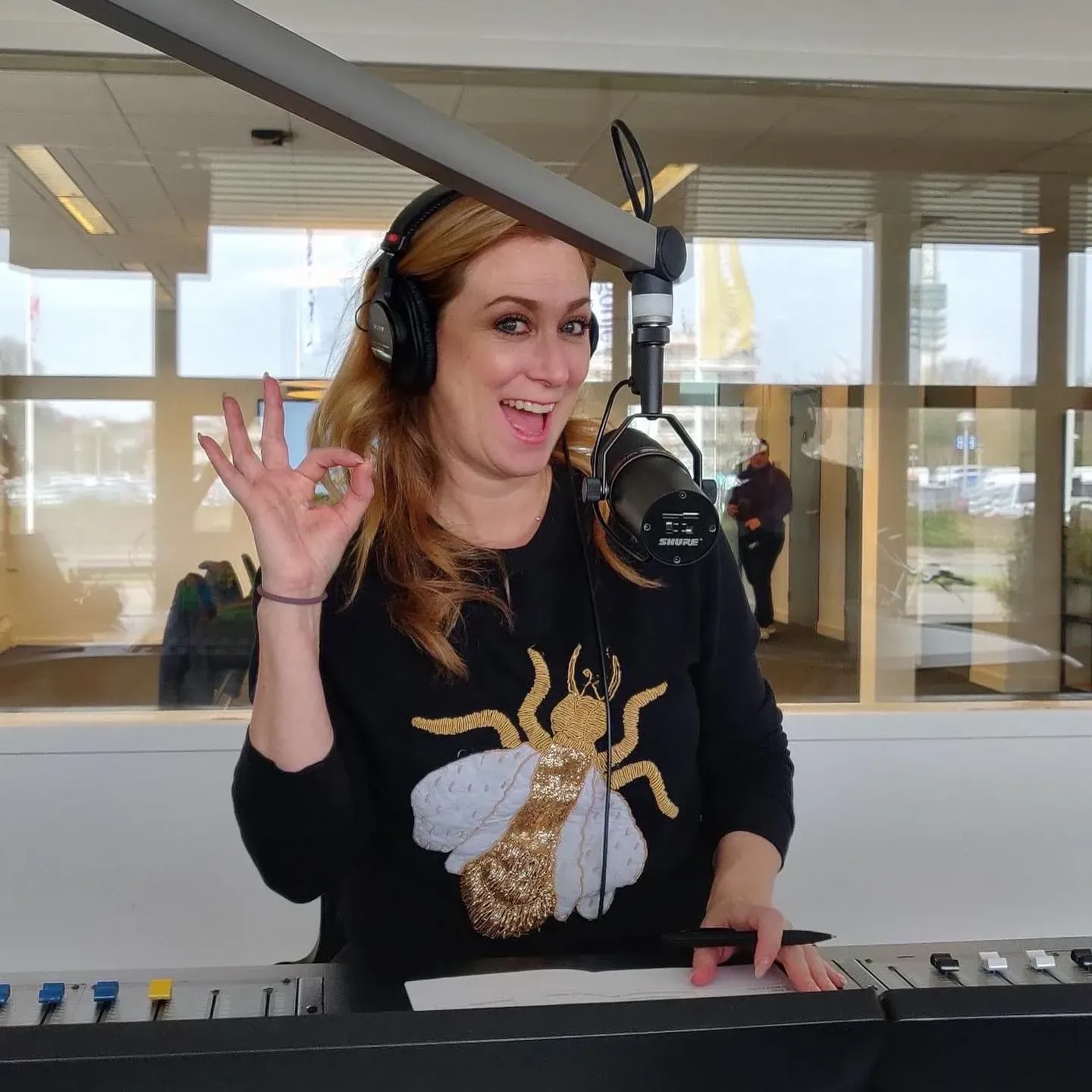 Presentatrice met koptelefoon achter de microfoon in de radiostudio